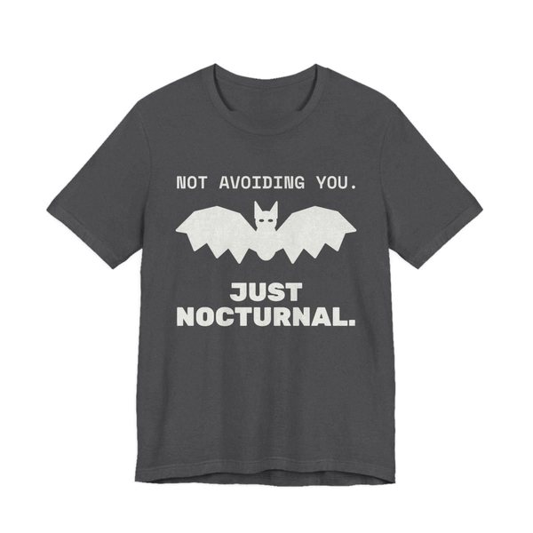 Dark Grey Heather t-shirt printed in off-white ink with “Not Avoiding You.” above a bat with wings spread, then “Just Nocturnal.”