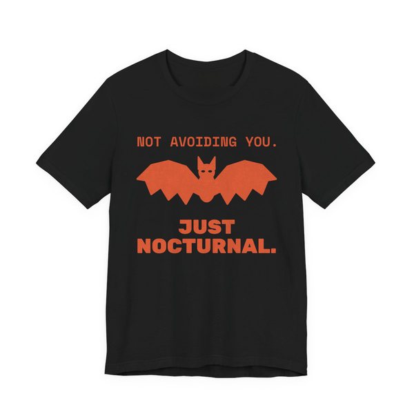 Black t-shirt printed in orange ink with “Not Avoiding You.” above a bat with wings spread, then “Just Nocturnal.”