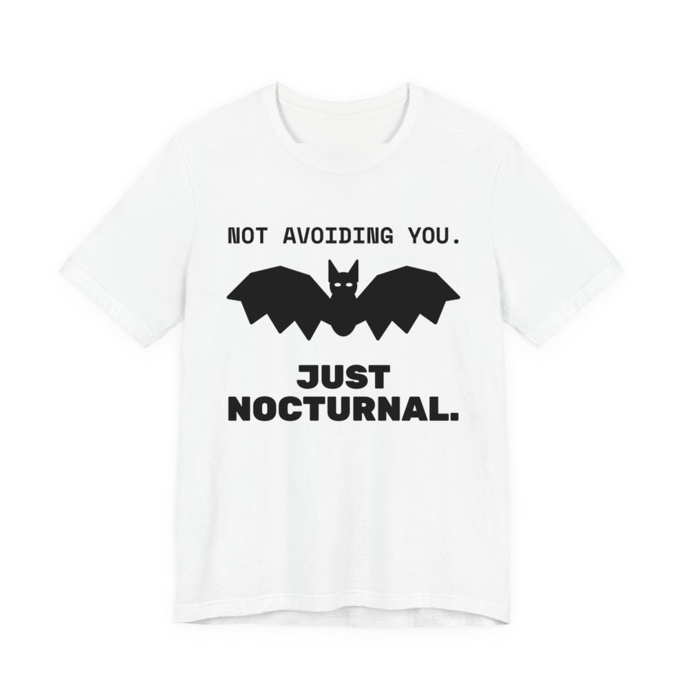 White t-shirt printed in dark ink with “Not Avoiding You.” above a bat with wings spread, then “Just Nocturnal.”
