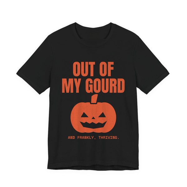 Black t-shirt printed in orange ink with “Out of My Gourd” above a grinning jack-o'-lantern, with “And frankly, thriving.”