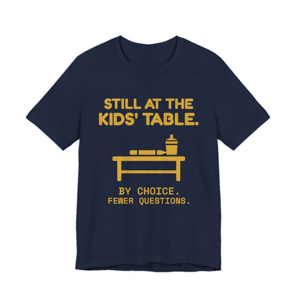 Navy t-shirt printed in gold ink with the words “Still at the Kids' Table.”
